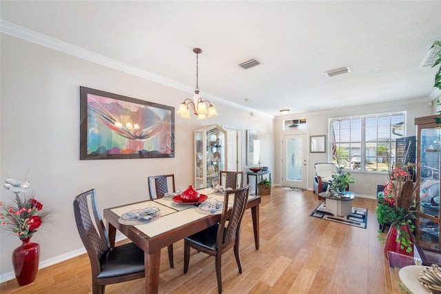 708 Sandy Hills Ave, Tarpon Springs, FL 34689 - dining room with light wood finished floors, a chandelier, and ornamental molding