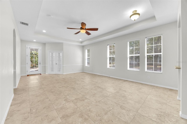 empty room with ceiling fan, visible vents, arched walkways, a raised ceiling, and recessed lighting