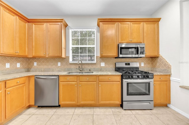 kitchen with decorative backsplash, a sink, baseboards, stainless steel appliances, and light tile patterned flooring