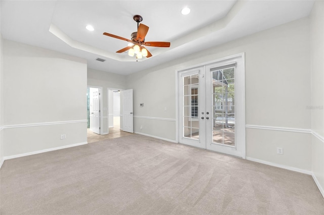 carpeted empty room featuring a tray ceiling, baseboards, french doors, and visible vents