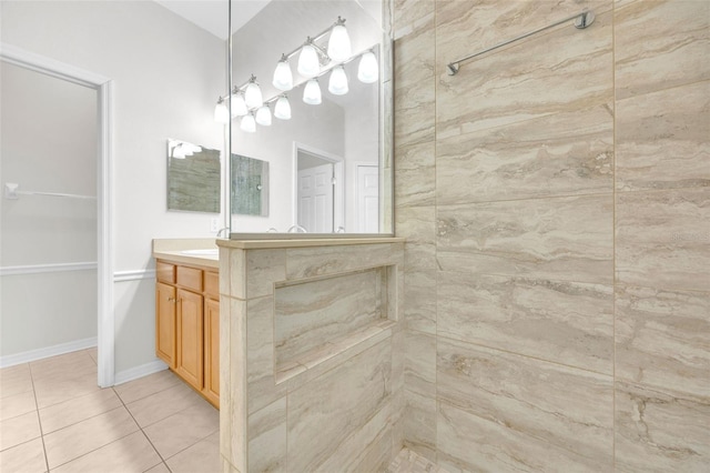 full bathroom with vanity, baseboards, tile patterned flooring, and tiled shower