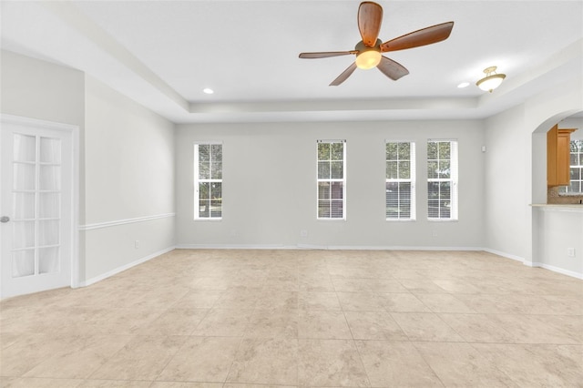 unfurnished room featuring light tile patterned flooring, ceiling fan, a raised ceiling, arched walkways, and recessed lighting