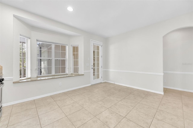 unfurnished room with arched walkways, baseboards, recessed lighting, and tile patterned flooring