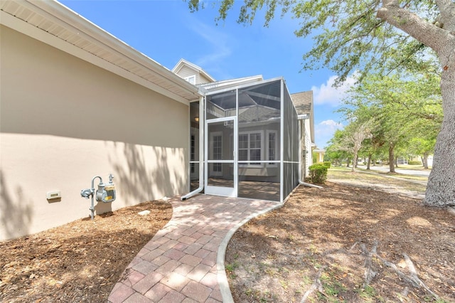 exterior space with glass enclosure, a patio, and stucco siding