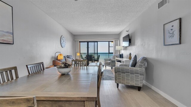 13720 Gulf Blvd Unit 305, Madeira Beach, FL 33708 - dining room featuring a textured ceiling, visible vents, wood finished floors, and baseboards