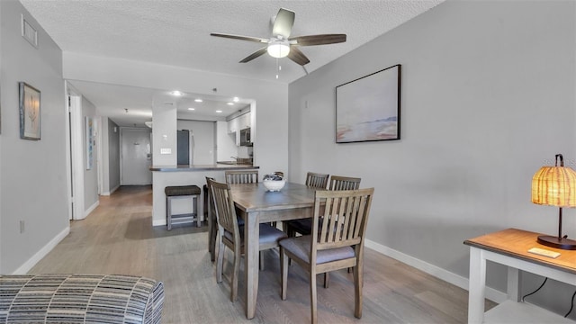 13720 Gulf Blvd Unit 305, Madeira Beach, FL 33708 - dining room featuring a ceiling fan, baseboards, and light wood-type flooring