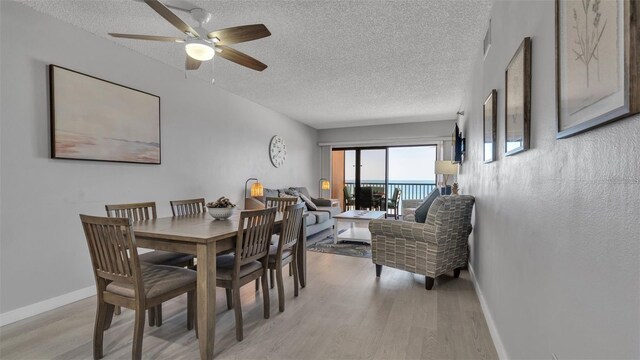 13720 Gulf Blvd Unit 305, Madeira Beach, FL 33708 - dining room with light wood finished floors, a textured ceiling, a ceiling fan, and baseboards