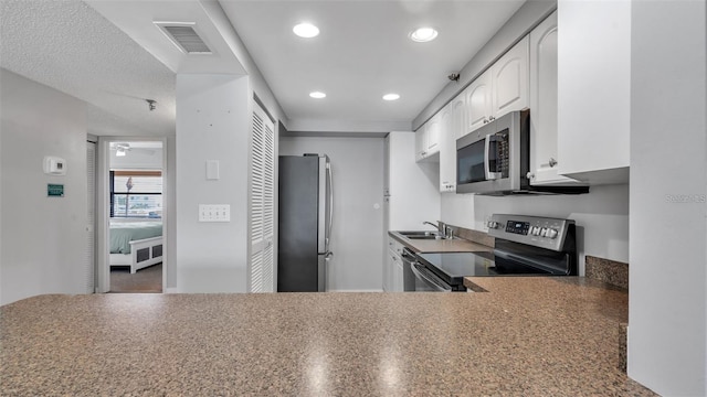 13720 Gulf Blvd Unit 305, Madeira Beach, FL 33708 - kitchen featuring white cabinets, a sink, appliances with stainless steel finishes, visible vents, and recessed lighting