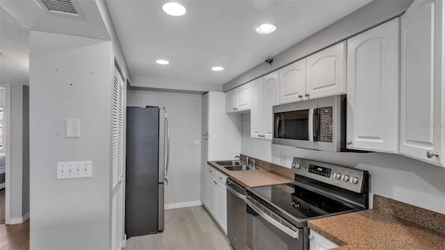 13720 Gulf Blvd Unit 305, Madeira Beach, FL 33708 - kitchen with white cabinetry, stainless steel appliances, light wood finished floors, and a sink
