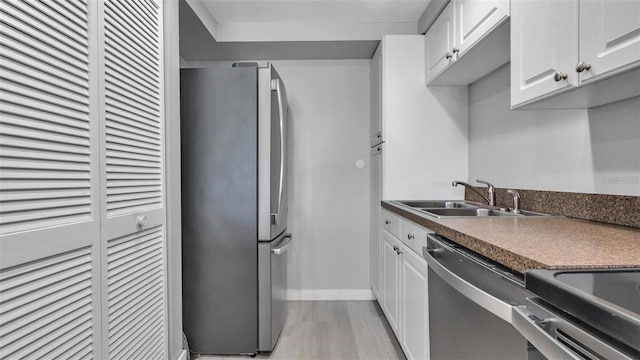 13720 Gulf Blvd Unit 305, Madeira Beach, FL 33708 - kitchen with appliances with stainless steel finishes, white cabinets, light wood finished floors, and a sink