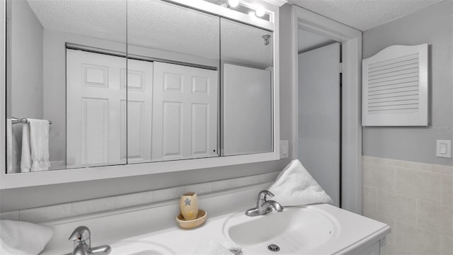 13720 Gulf Blvd Unit 305, Madeira Beach, FL 33708 - full bath featuring a textured ceiling, a sink, double vanity, and tile walls