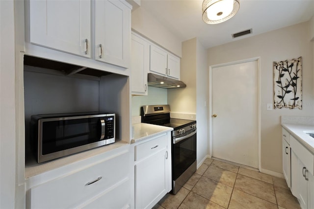 5561 24th Ter N, Saint Petersburg, FL 33710 - kitchen featuring appliances with stainless steel finishes, under cabinet range hood, white cabinetry, light countertops, and light tile patterned floors