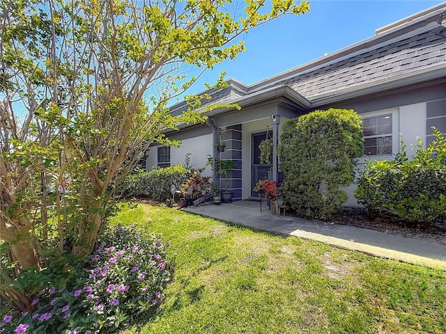 1241 N Mcmullen Booth Rd, Clearwater, FL 33759 - doorway to property featuring a lawn, stucco siding, and roof with shingles