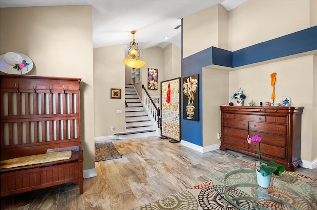 entrance foyer featuring high vaulted ceiling, baseboards, wood finished floors, and stairs