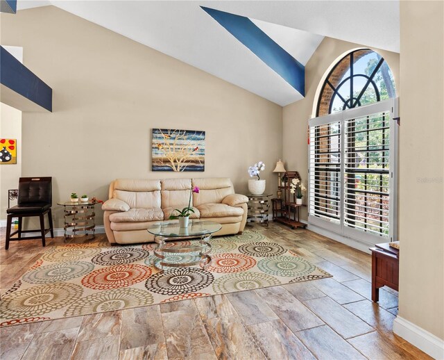 living area featuring baseboards and high vaulted ceiling