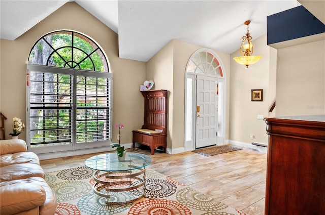 foyer featuring vaulted ceiling, light wood finished floors, and baseboards