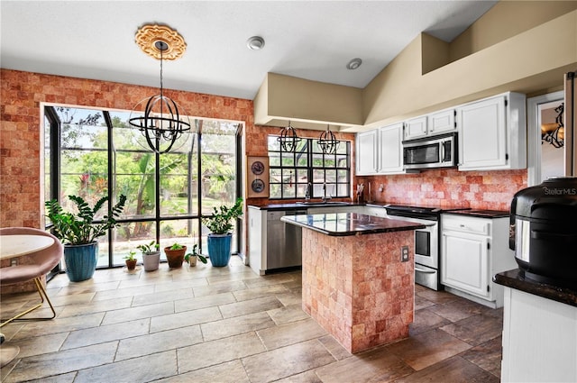 kitchen featuring dark countertops, a center island, an inviting chandelier, white cabinets, and appliances with stainless steel finishes