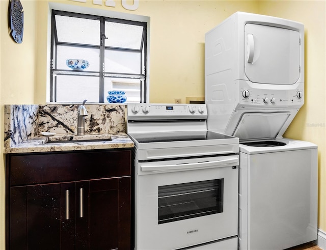 kitchen featuring stacked washer and dryer, light countertops, a sink, and electric range