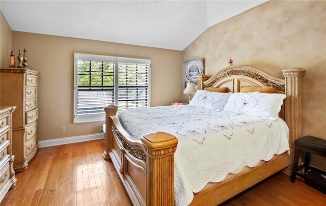bedroom featuring baseboards, vaulted ceiling, and light wood-type flooring