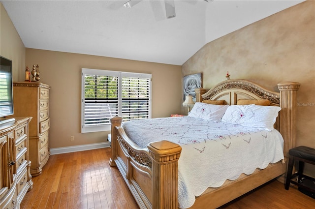 bedroom with vaulted ceiling, light wood-style floors, and baseboards