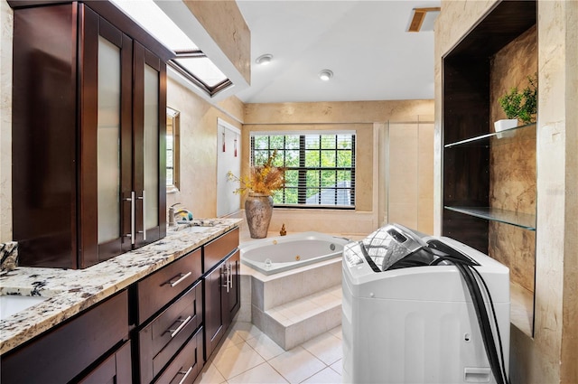 bathroom featuring double vanity, tile patterned flooring, a tub with jets, and a sink