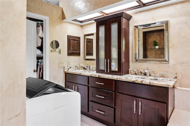 full bath featuring a walk in closet, tile patterned floors, a sink, and double vanity