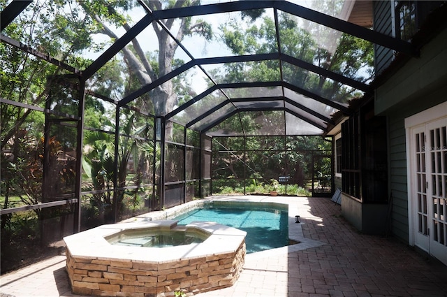 view of pool with a lanai, a patio, a pool with connected hot tub, and french doors