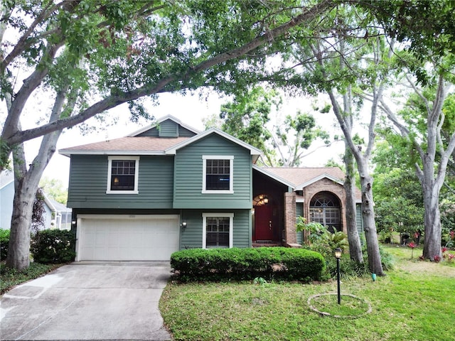 tri-level home featuring concrete driveway, roof with shingles, a front yard, and a garage