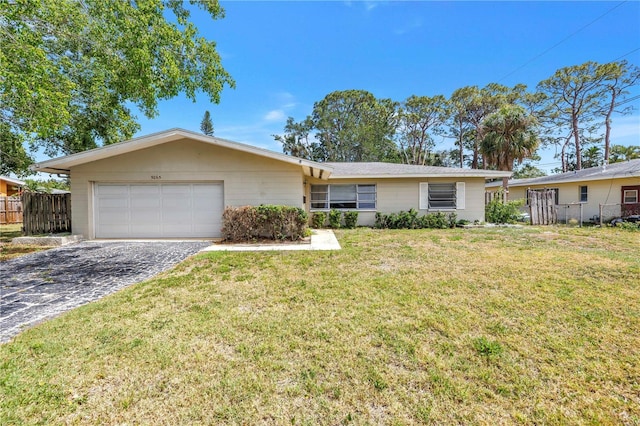 ranch-style home with an attached garage, fence, driveway, and a front lawn