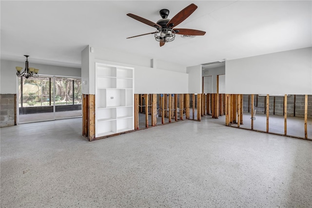 unfurnished room with ceiling fan with notable chandelier and speckled floor