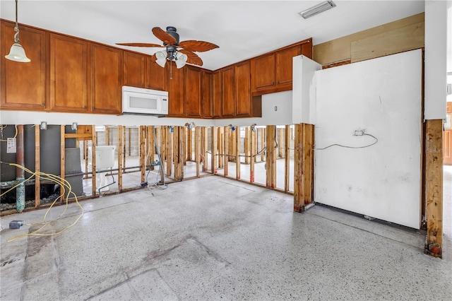 kitchen featuring speckled floor, visible vents, a ceiling fan, white microwave, and pendant lighting