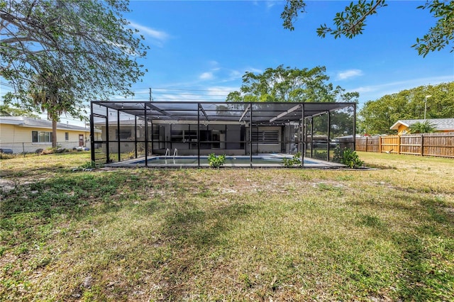 rear view of property featuring a patio area, glass enclosure, a fenced backyard, a yard, and a fenced in pool