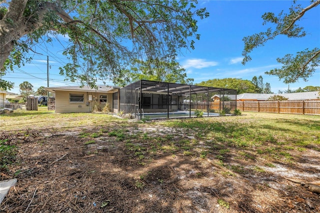 view of yard with a fenced backyard, a fenced in pool, and glass enclosure