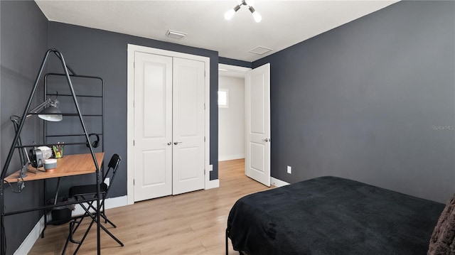 bedroom featuring baseboards, a closet, light wood finished floors, and visible vents