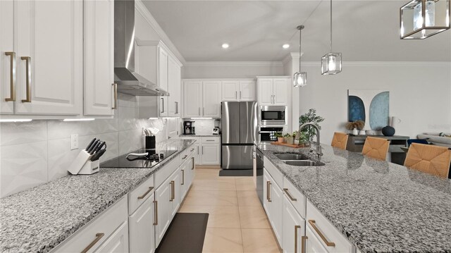 kitchen featuring light tile patterned floors, a sink, stainless steel appliances, white cabinets, and wall chimney range hood