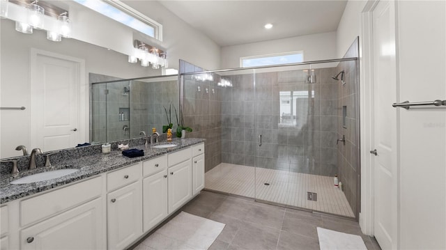 bathroom with double vanity, a shower stall, and a sink