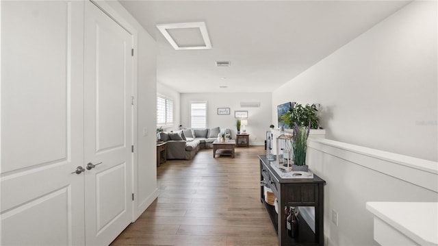 hallway featuring attic access, visible vents, and wood finished floors