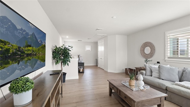 living area featuring baseboards, light wood finished floors, and attic access