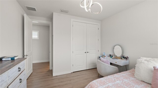 bedroom featuring light wood-style floors, a closet, an inviting chandelier, and visible vents
