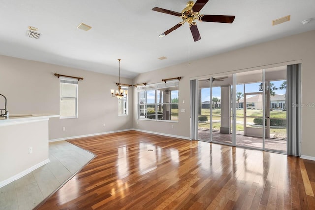 unfurnished dining area featuring visible vents, baseboards, wood finished floors, and ceiling fan with notable chandelier