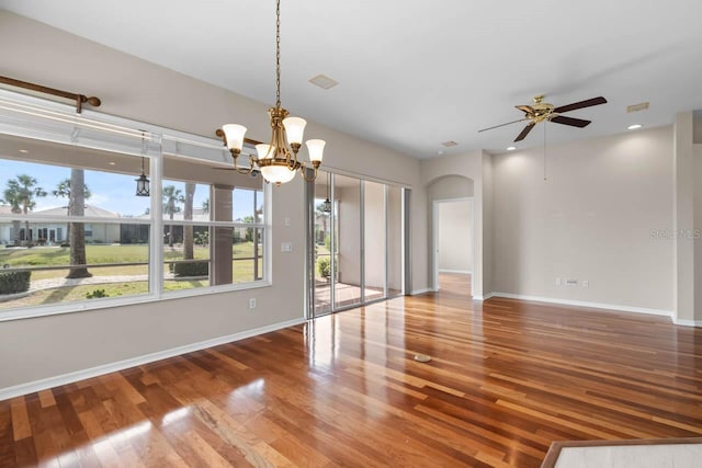 unfurnished room featuring baseboards, arched walkways, ceiling fan with notable chandelier, and wood finished floors