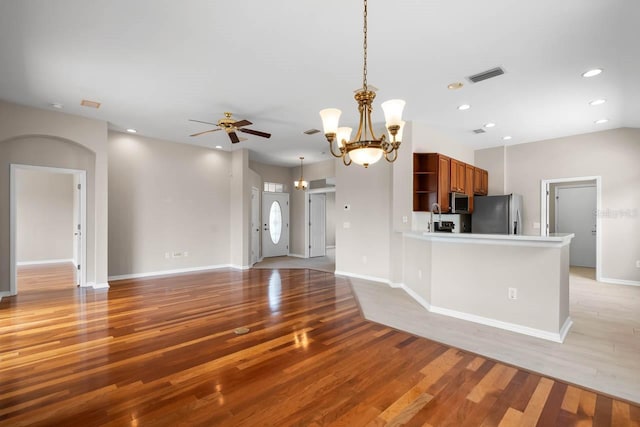 kitchen with open shelves, light wood-type flooring, visible vents, appliances with stainless steel finishes, and ceiling fan with notable chandelier