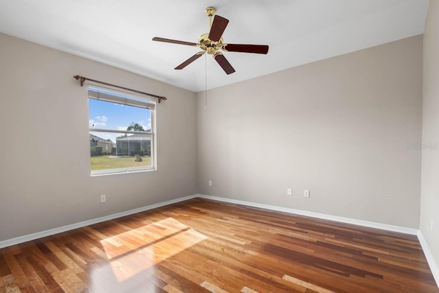 empty room featuring a ceiling fan, wood finished floors, and baseboards