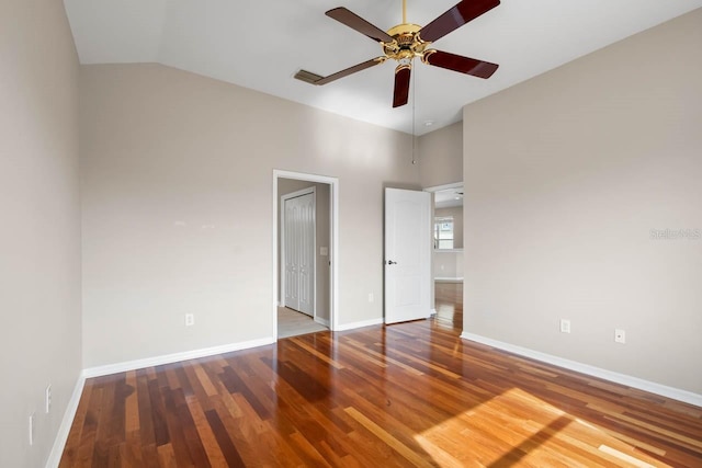 unfurnished bedroom with lofted ceiling, visible vents, wood finished floors, and baseboards