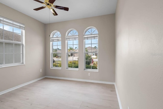 spare room with light wood-style floors, a ceiling fan, and baseboards