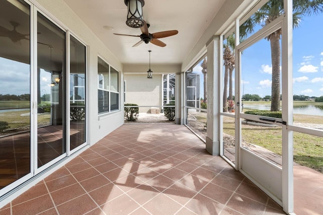 unfurnished sunroom featuring a ceiling fan and a water view