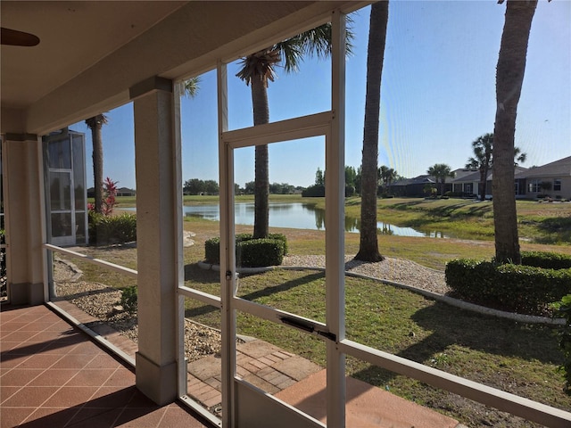 sunroom / solarium featuring tile patterned floors, a water view, and plenty of natural light