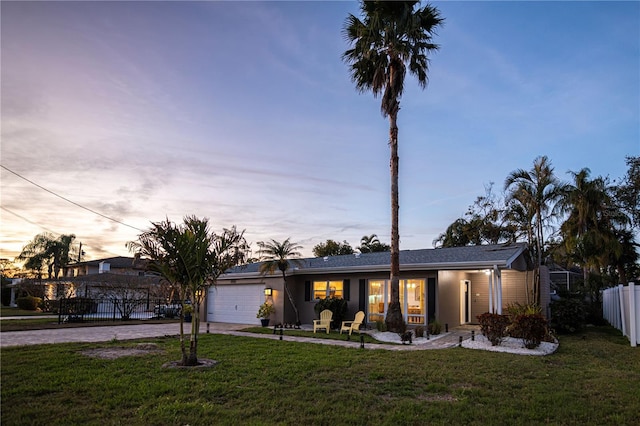 view of front of home with concrete driveway, a front lawn, fence, and a garage