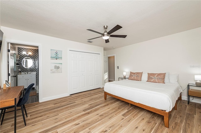 bedroom featuring ensuite bath, a closet, light wood finished floors, and baseboards