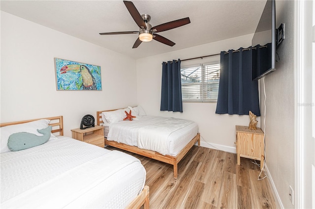 bedroom featuring ceiling fan, baseboards, and light wood-style floors